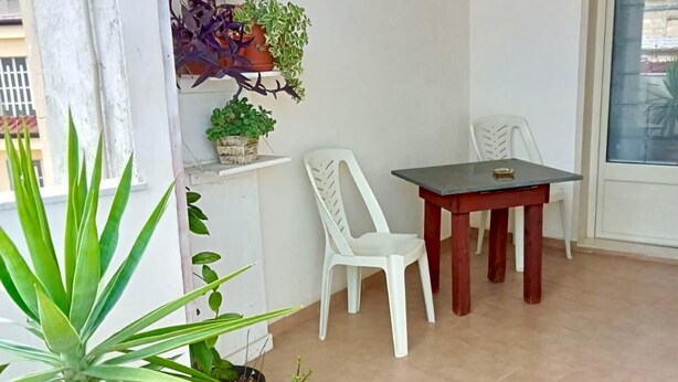 A small balcony with a table and chairs, potted plants, and a window with a view. - The sculptor's retreat (Niscemi)