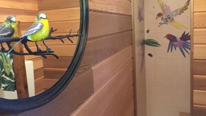 A wooden interior with a mirror reflecting two birds on a branch. - Lake Como Dream Treehouse (Como)