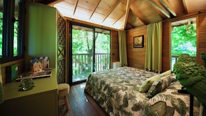 A bedroom with a bed, a desk, a chair, and a balcony with a view of trees. - Lake Como Dream Treehouse (Como)