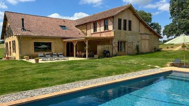Ein zweistöckiges Haus mit einem Pool davor.