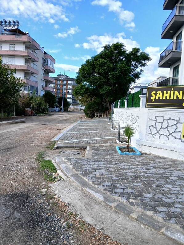 A paved pathway leading to a building with a sign reading "ŞAHIN". - Şahiner Apart Otel (Finike)