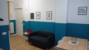 A room with a black sofa, a wooden table with a decorative sphere, and a wall with framed inspirational quotes. - Room rental for vacation, with bathroom in room 100 mt from subway  (Roma)