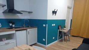 A compact kitchen with a sink, stove, and cabinets, adjacent to a dining area with a table and chairs. - Room rental for vacation, with bathroom in room 100 mt from subway  (Roma)