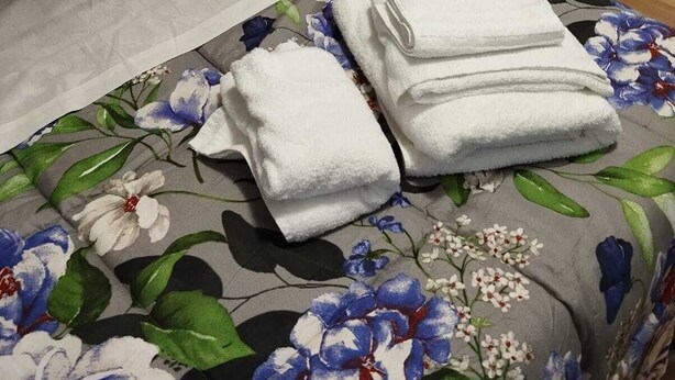 A bed with floral bedding, white towels, and a wooden headboard. - Room rental for vacation, with bathroom in room 100 mt from subway  (Roma)