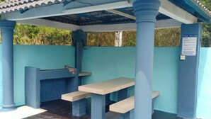 A covered outdoor seating area with a pool rules sign, benches, and a water feature.