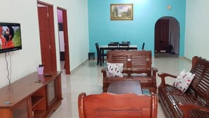 A living room with a TV, wooden furniture, and a painting on the wall.