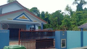 A building with a blue and white facade, a gated entrance, and a small window.