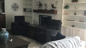 Een woonkamer met een open haard, een bank, een salontafel en een televisie.