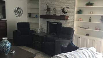 Una Smart TV, una chimenea, libros, una pantalla de ordenador