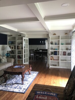 Un salon spacieux avec une table basse en bois, un tapis à motifs et une pancarte indiquant « Bienvenue ».