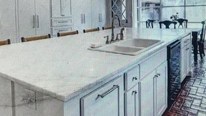 Een moderne keuken met een groot eiland, inbouwapparatuur en uitzicht op het buitengebied.