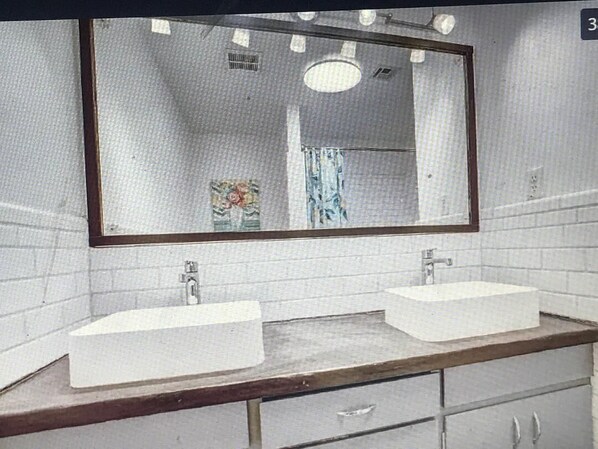 Une salle de bain avec deux lavabos, un miroir et un rideau de douche.