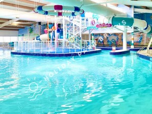An indoor swimming pool with a water slide and a dolphin-themed mural. - Seal Bay Private Rentals (Chichester)