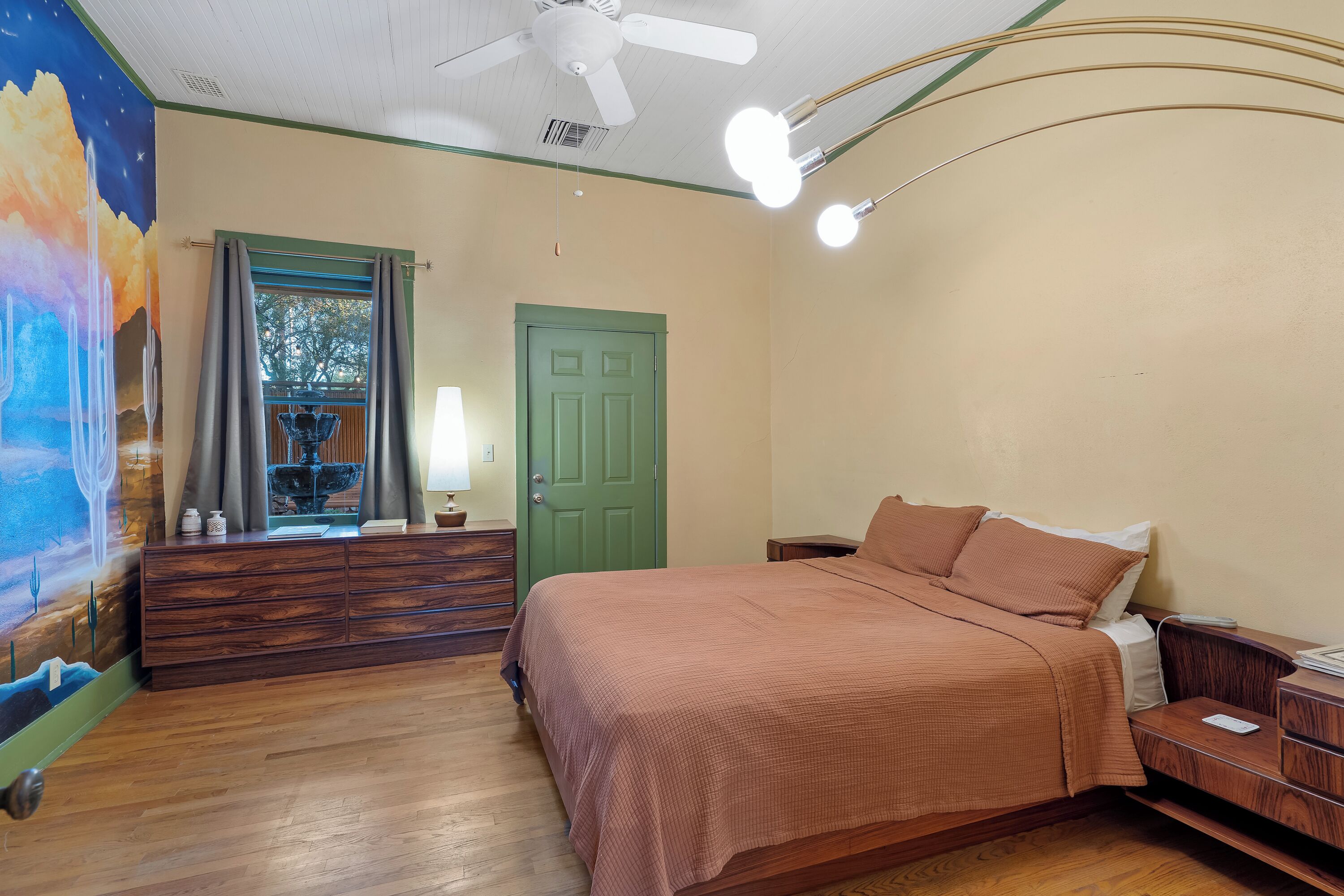 Un dormitorio con cama, cómoda y un mural en la pared.