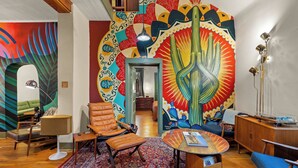 Un saló modern amb un mural colorit, un terra de fusta i mobles de pell i teixit.