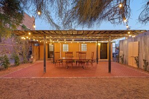 Une terrasse extérieure dotée d’une pergola, de guirlandes lumineuses et d’une table à manger avec des chaises.