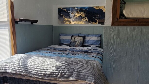 Ein Schlafzimmer mit einem Bett, einer Wanddekoration und einem Fenster mit Jalousien.