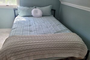 Ein Bett mit gesteppter Bettdecke und einer Strickdecke.