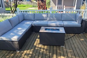 A sectional sofa with a built-in fire feature on a wooden deck. - Big home - walk to the beach - First year offered (Ludington)