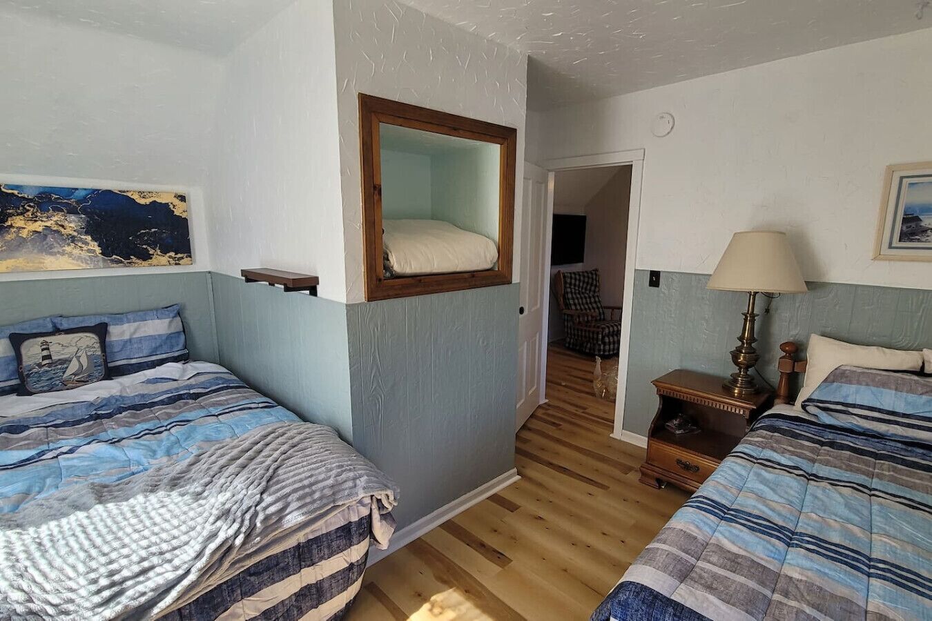 Un dormitorio con dos camas, un espejo, una lámpara y un cuadro en la pared.