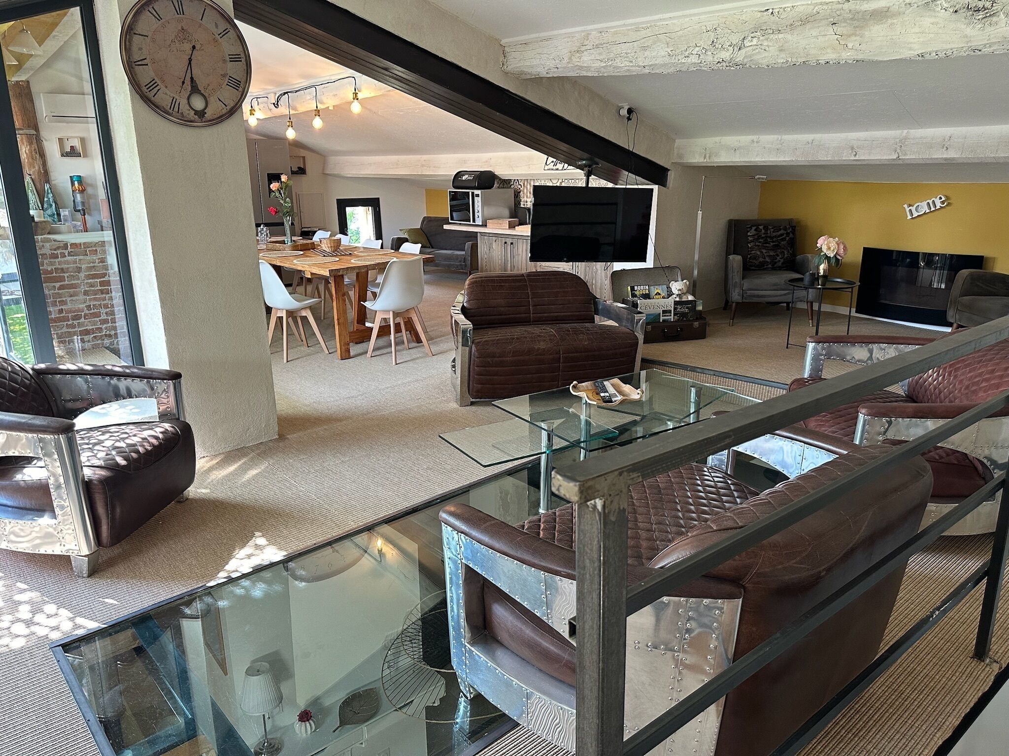 A spacious living area with a high ceiling, a dining table, and modern furniture.