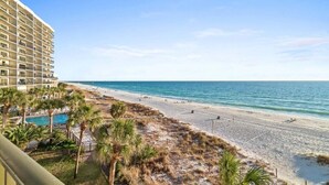 A beachfront hotel with a pool, beach access, and palm trees. - Fall Deals + Snowbird Rates | Gulf Front Beach Escape (Panama City Beach)