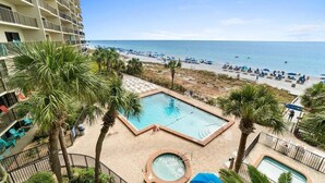 A hotel pool area with a view of the beach, palm trees, and a clear sky. - Fall Deals + Snowbird Rates | Gulf Front Beach Escape (Panama City Beach)