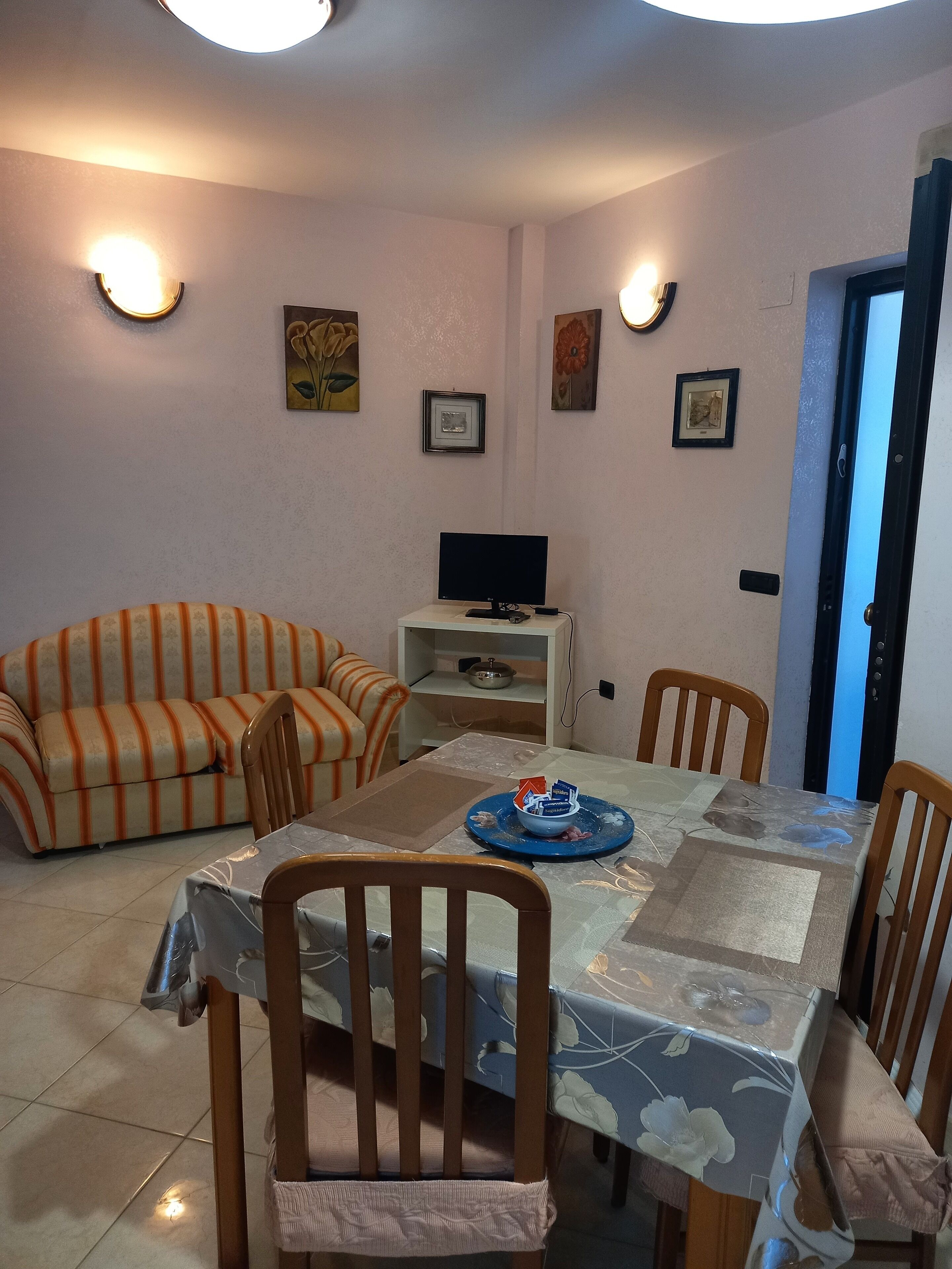 A dining area with a table, chairs, a sofa, and a television.