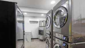 A laundry room with stacked washers and dryers, a water dispenser, and an air conditioning unit. - Motel 6 Hickory, NC (Hickory)