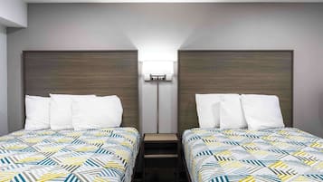 Una habitación de hotel con dos camas individuales, una mesita de noche entre ellas y una lámpara fijada a la pared.