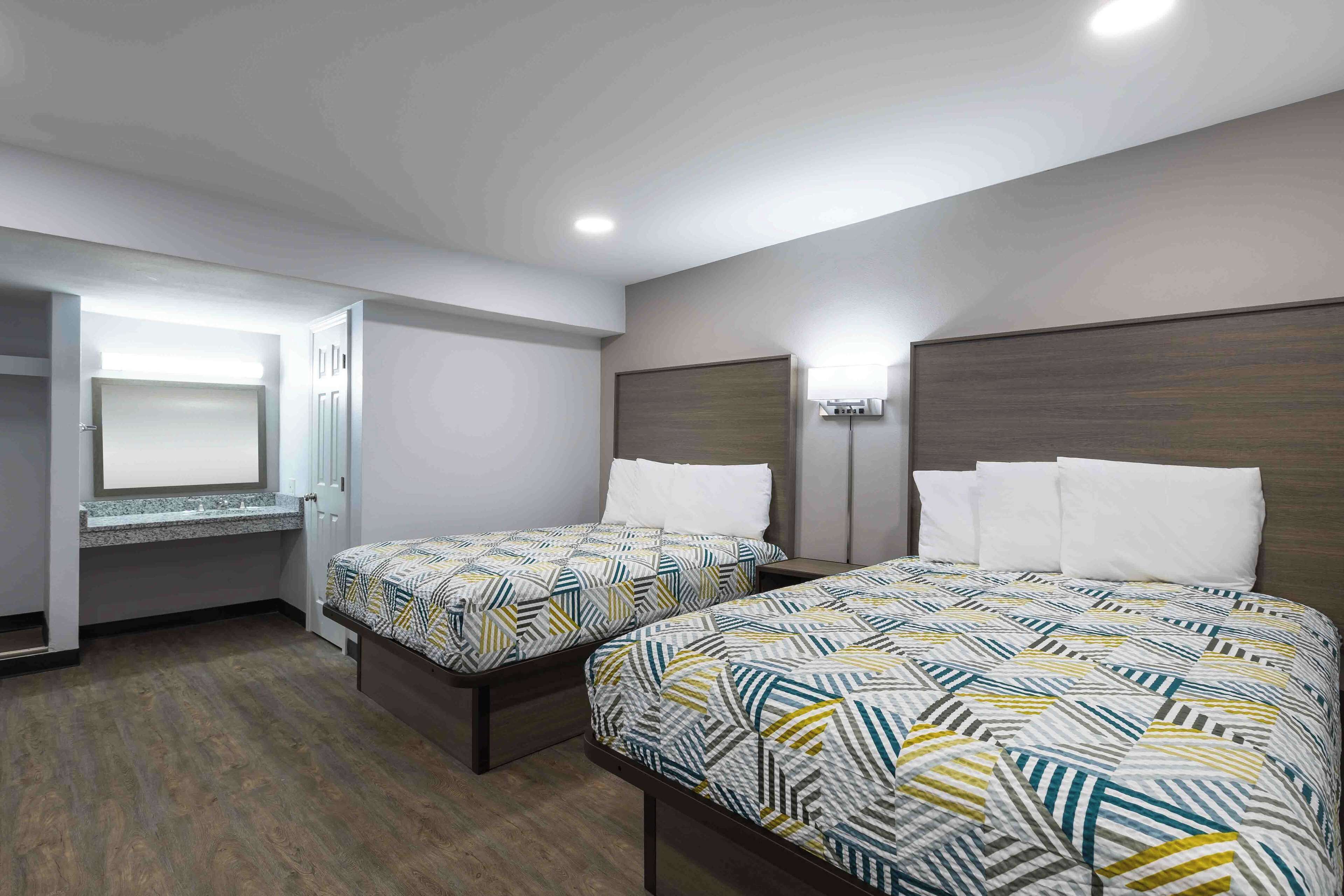 A hotel room with two beds, a built-in desk, and a large mirror.