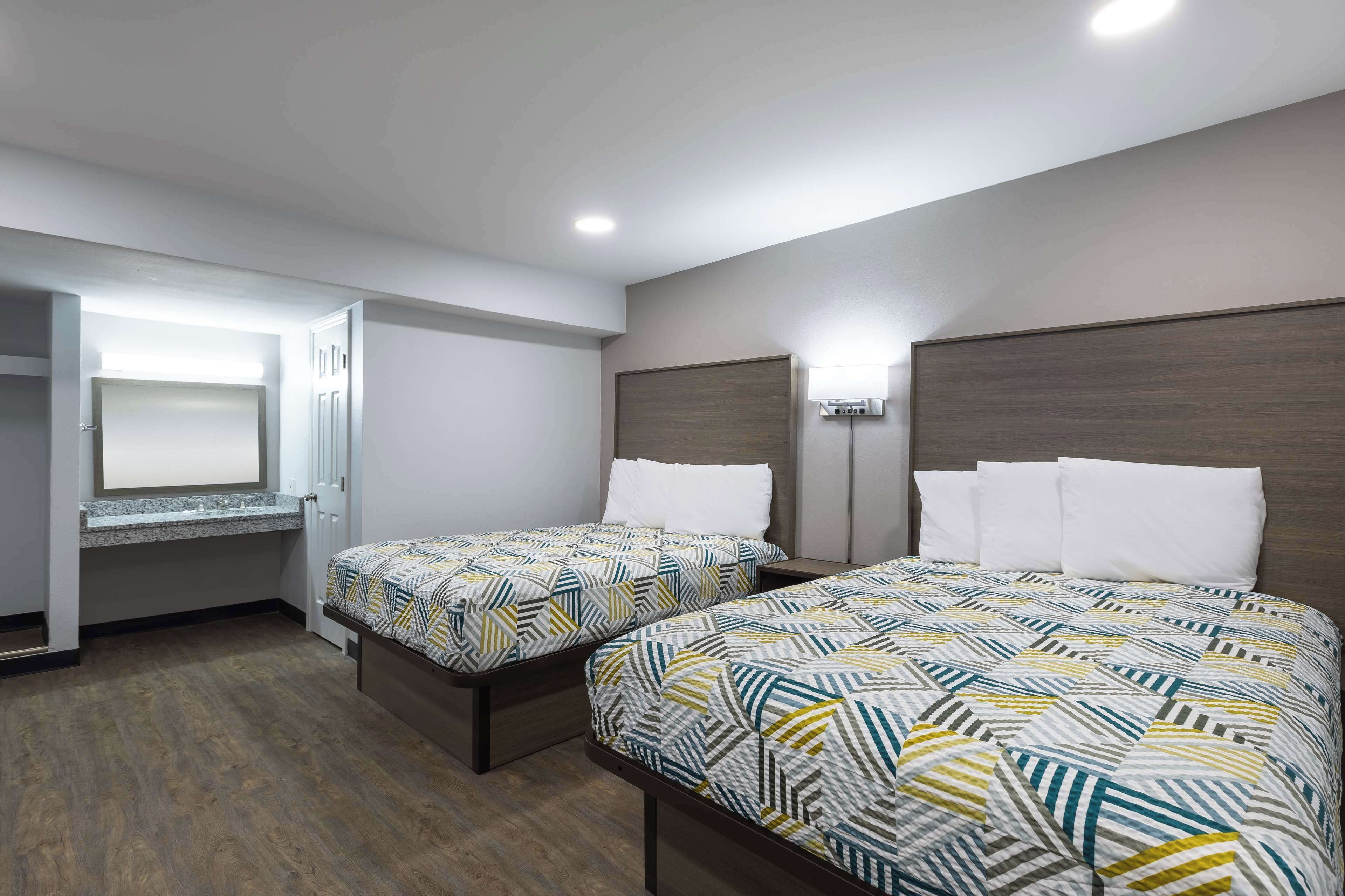 Une chambre d’hôtel avec deux lits, un bureau intégré et une fenêtre.