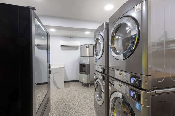 A laundry room with stacked washers and dryers, a water dispenser, and a small kitchenette area. - Studio 6 Hickory, NC (Hickory)