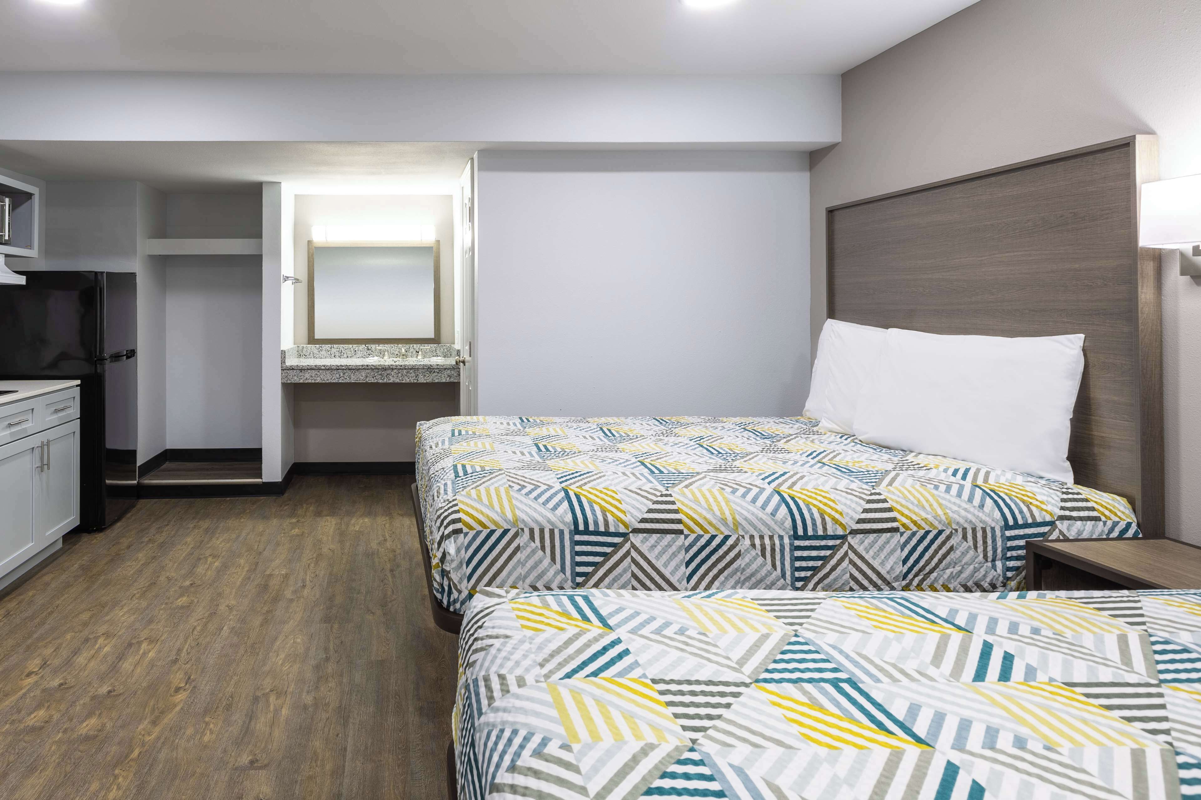A hotel room with two beds, a small kitchenette, and a walk-in closet.
