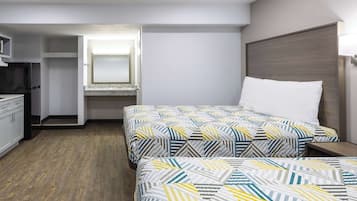 A hotel room with two beds, a small kitchenette, and a walk-in closet.
