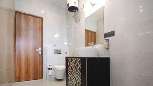 Uma casa de banho com porta de madeira, sanita, lavatório e espelho.