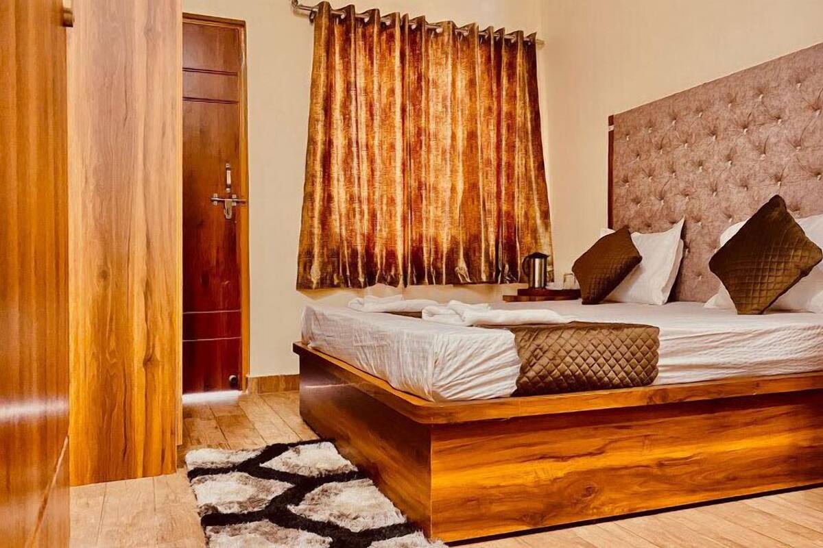 A bedroom with a wooden bed frame, a tufted headboard, and a large window with curtains.