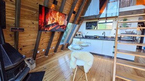 A cozy cabin interior with a fireplace, a dining area, and a kitchen with modern appliances. - Cabanas Lumberjack (Urubici)
