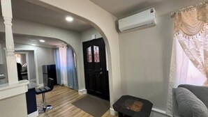 Sala de estar com uma porta preta, um sofá cinza e uma mesa pequena.