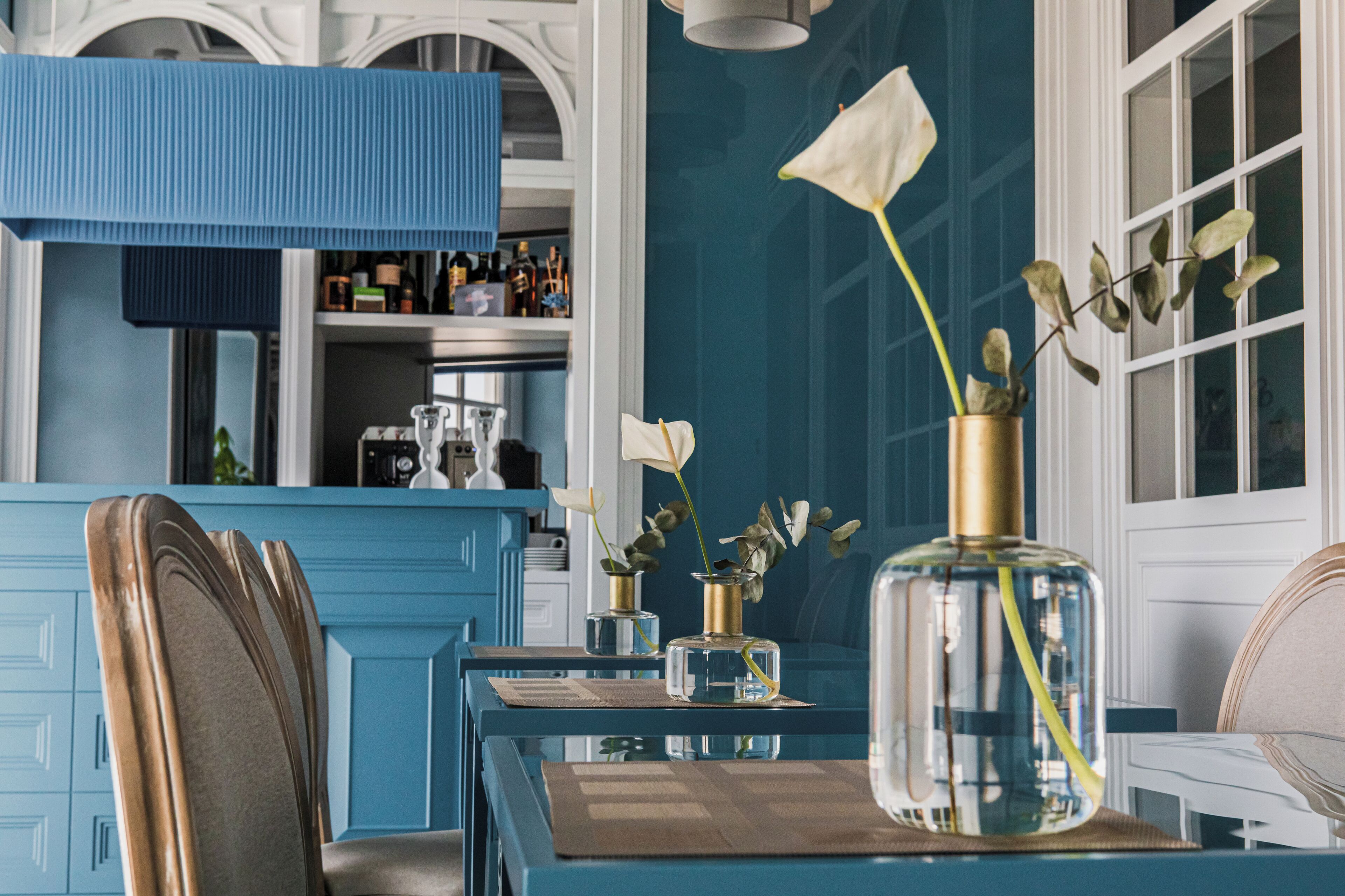 A dining area with a blue table, chairs, and a vase with flowers.
