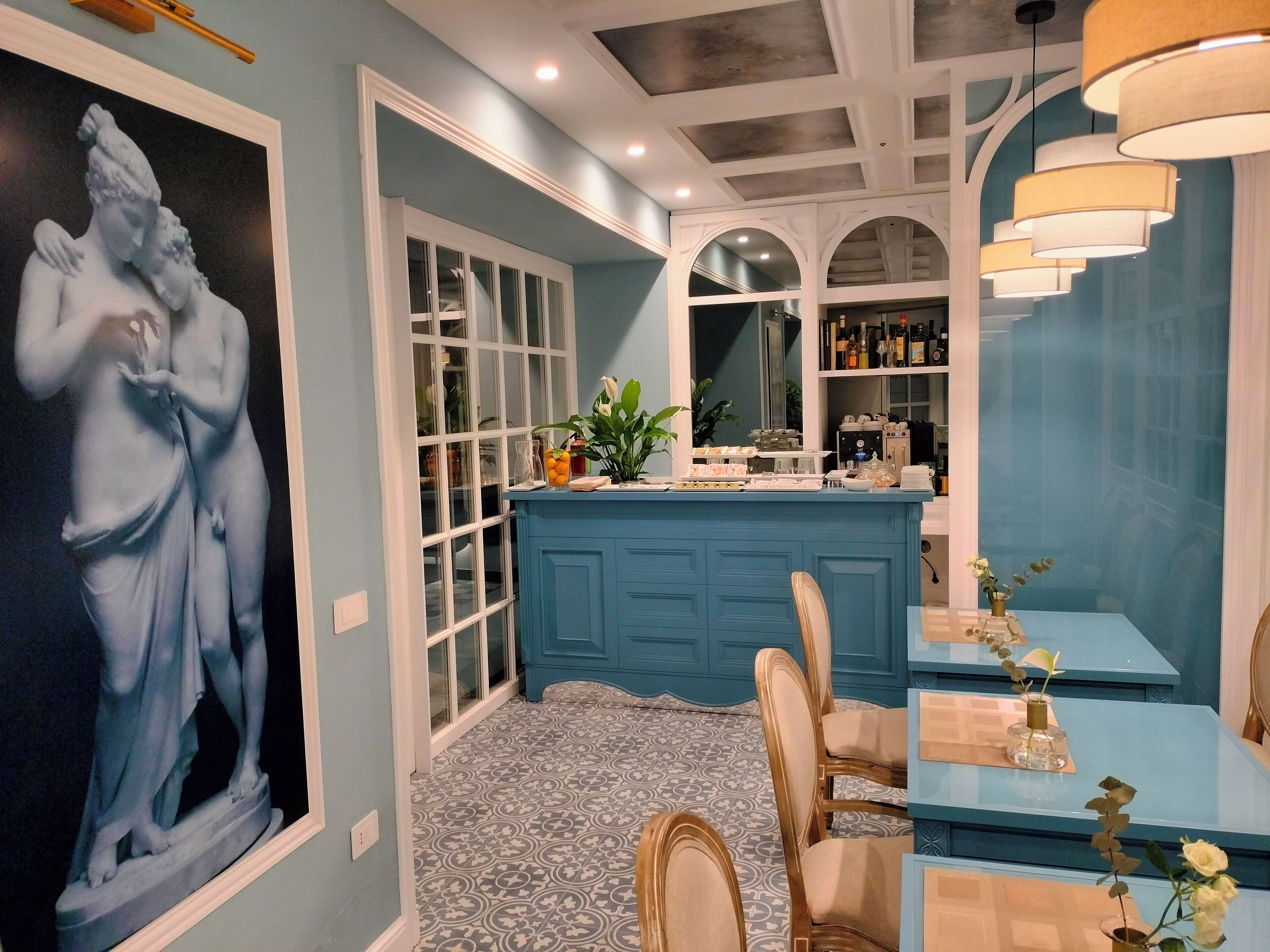 Habitación con una pared azul de acento, una obra de arte grande enmarco, una zona de bar azul con taburetes y un suelo estampado.