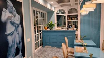 Habitación con una pared azul de acento, una obra de arte grande enmarco, una zona de bar azul con taburetes y un suelo estampado.