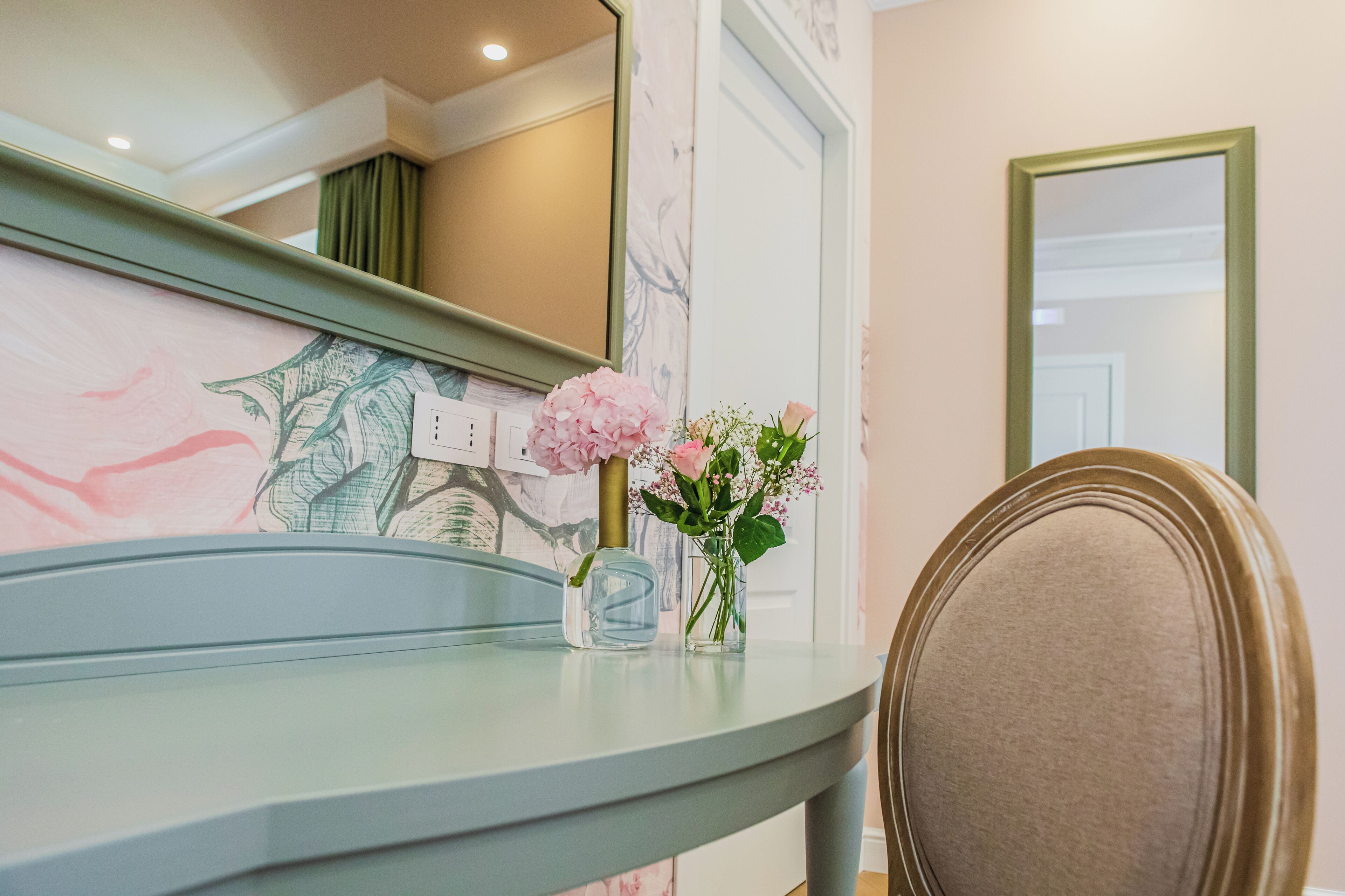 A bathroom with a marble wall, a mirror, a sink, and a chair.
