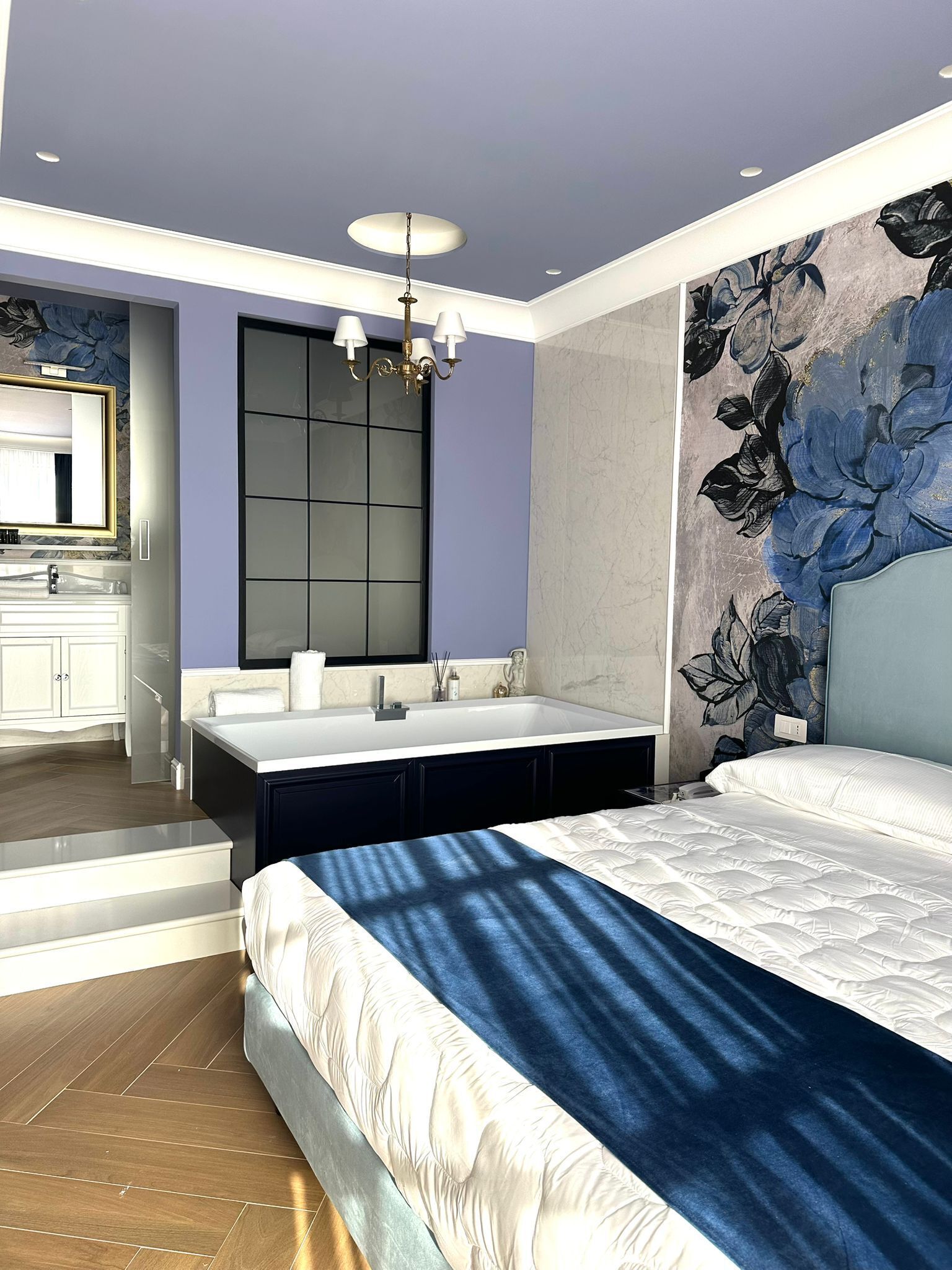 A modern bedroom with a large bed, a built-in vanity, and a large mirror.