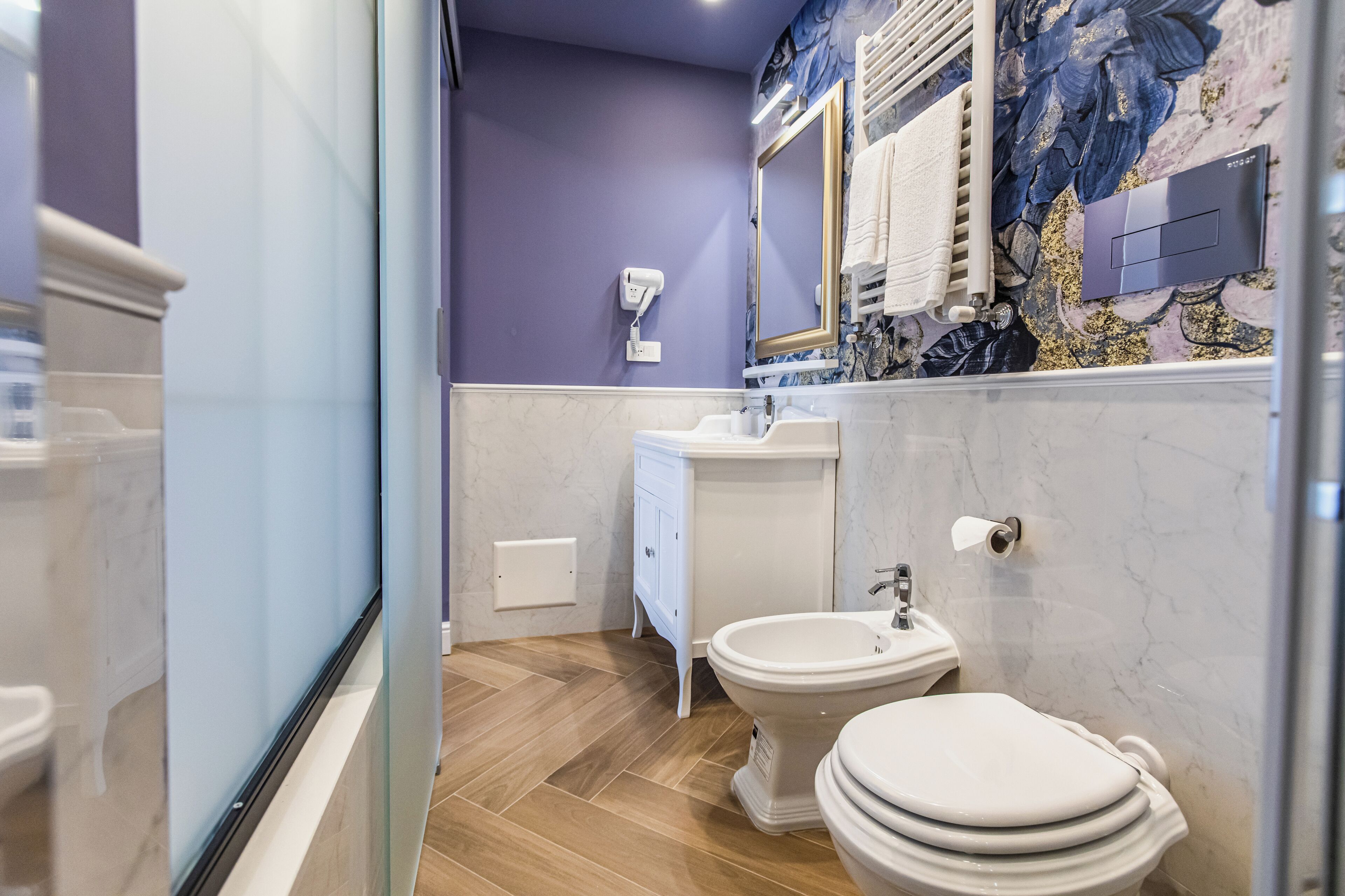 Un baño con lavamanos de mármol, inodoro y bidé.
