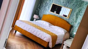 Een hotelkamer met een bed, nachtkastje, spiegel en een visgraatvloer.