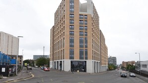A modern multi-story building with a prominent corner design, featuring a mix of glass and brick facades. - For Students Only Cosy Ensuite Rooms With Private Bathrooms at Dobbie's Point in Glasgow (Glasgow)