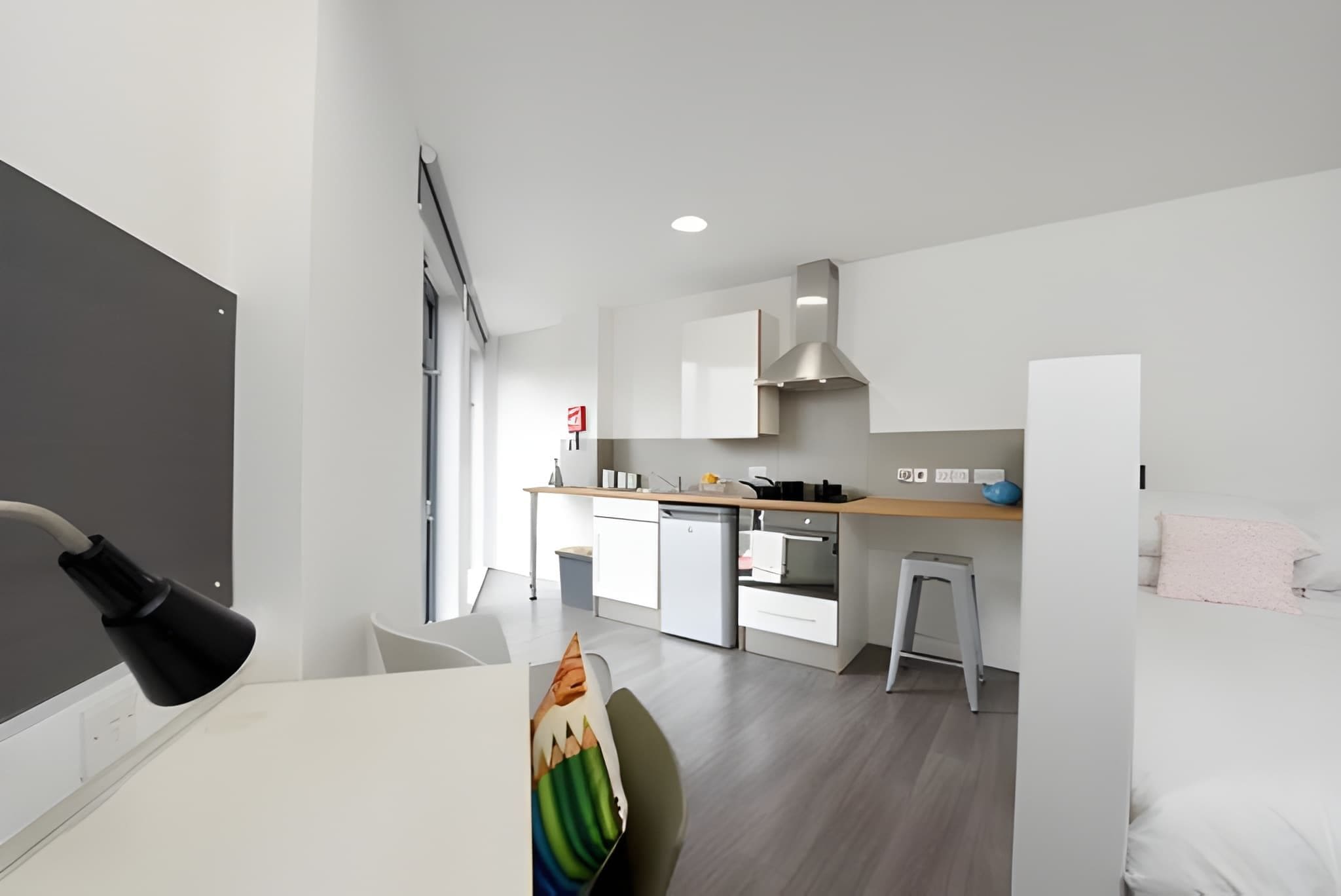 Une cuisine moderne avec des meubles blancs, un four encastré et un petit coin repas comprenant une table et des chaises blanches.