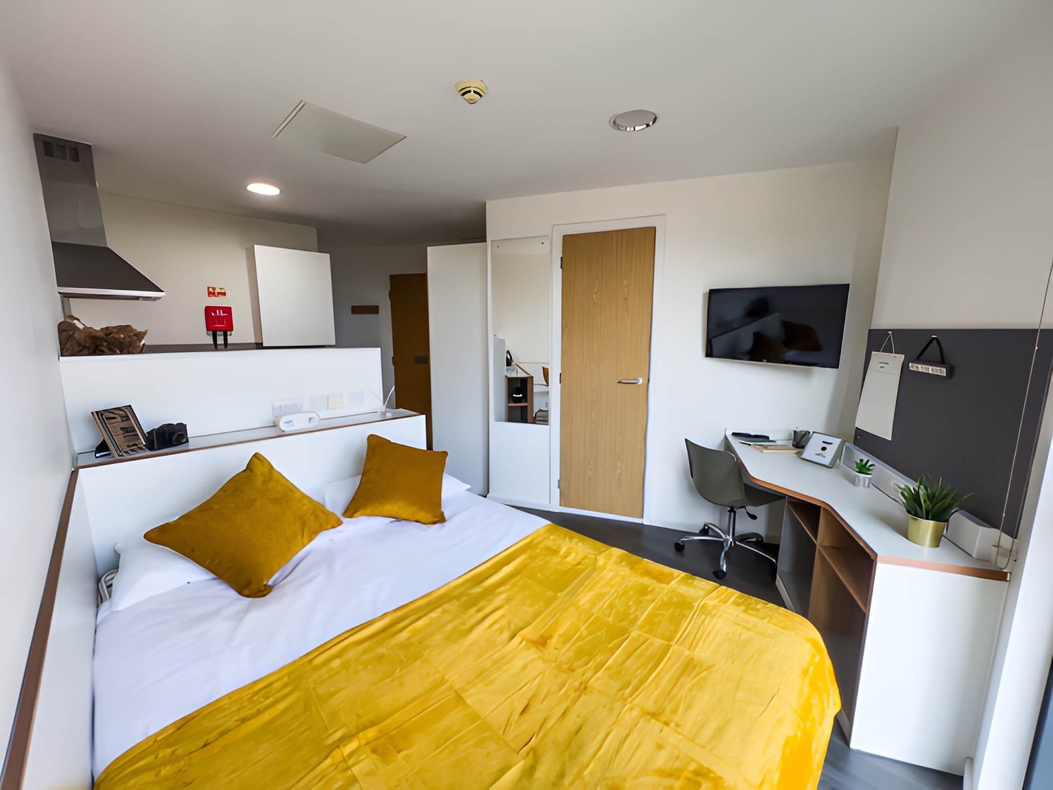 Une chambre d’hôtel moderne équipée d’un lit, d’un bureau, d’une chaise, d’une télévision et d’une armoire.