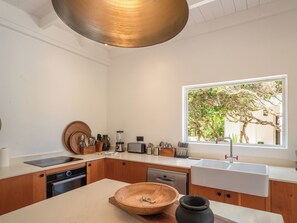 Une cuisine moderne avec des meubles en bois, une grande fenêtre et un saladier en bois servant de centre de table.
